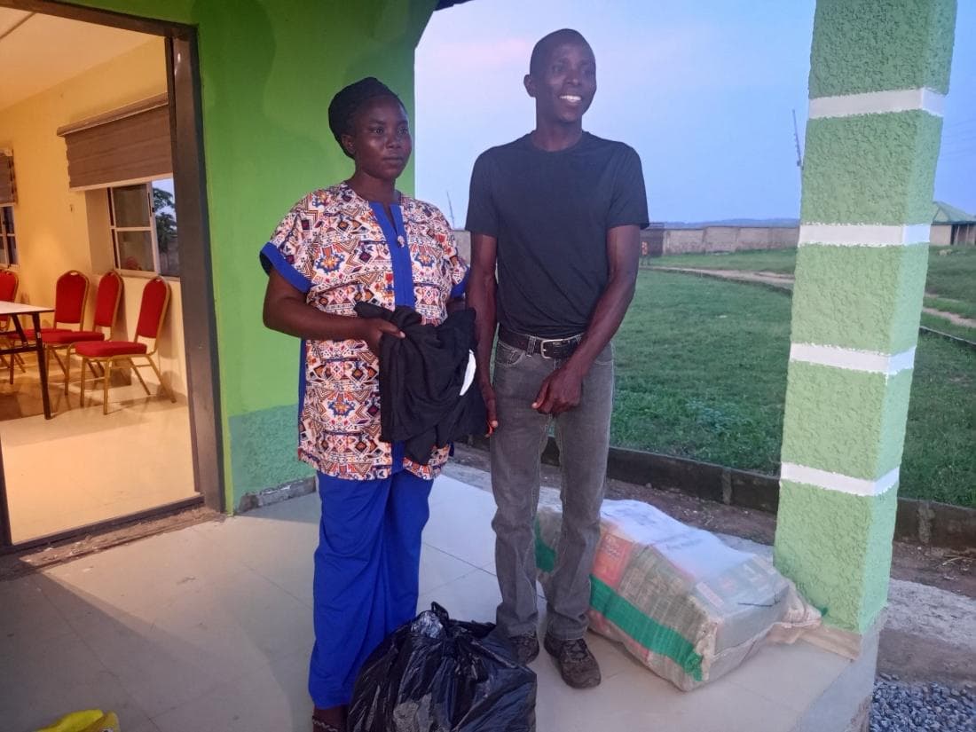 Two beneficiaries with the food and household supplies they received