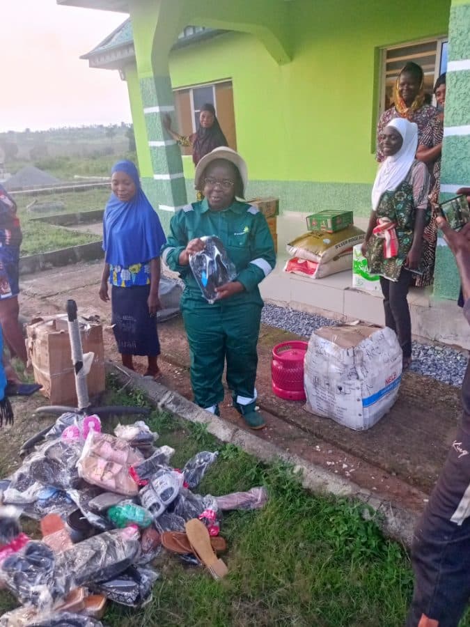 A member of the foundation's team in green overalls hands out clothing, footwear and household items